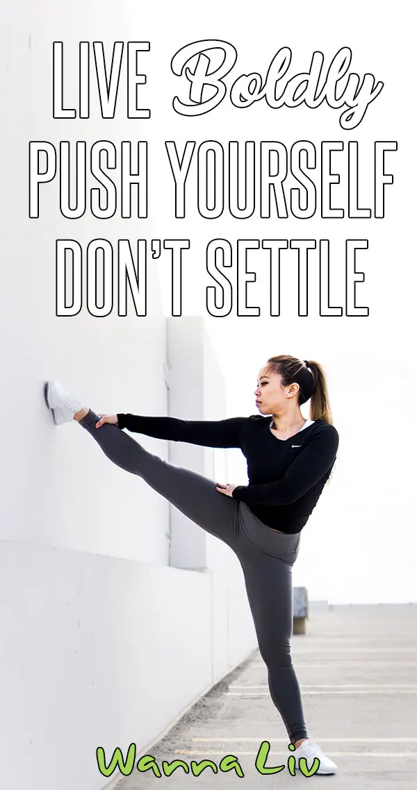 Woman outside stretching her leg on a wall with overlay text "Live Boldly | Push Yourself | Don't Settle"